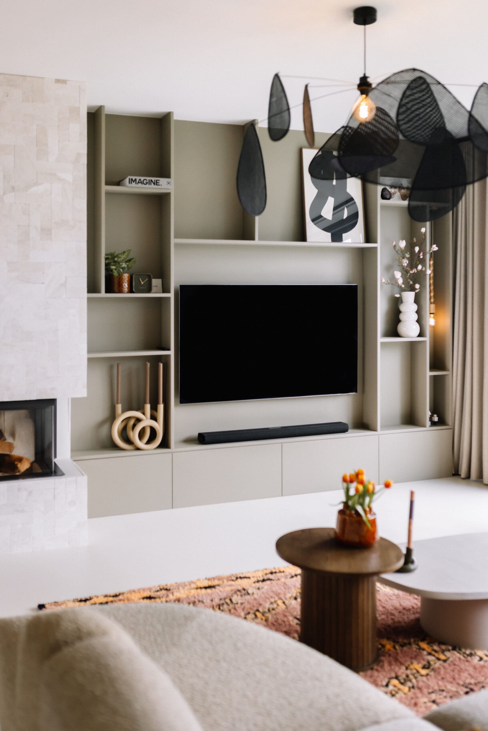 Maatwerk televisiewand met open vakken en gesloten opbergruimte in een warme taupe kleur, gestyled met vazen, planten en kunst
