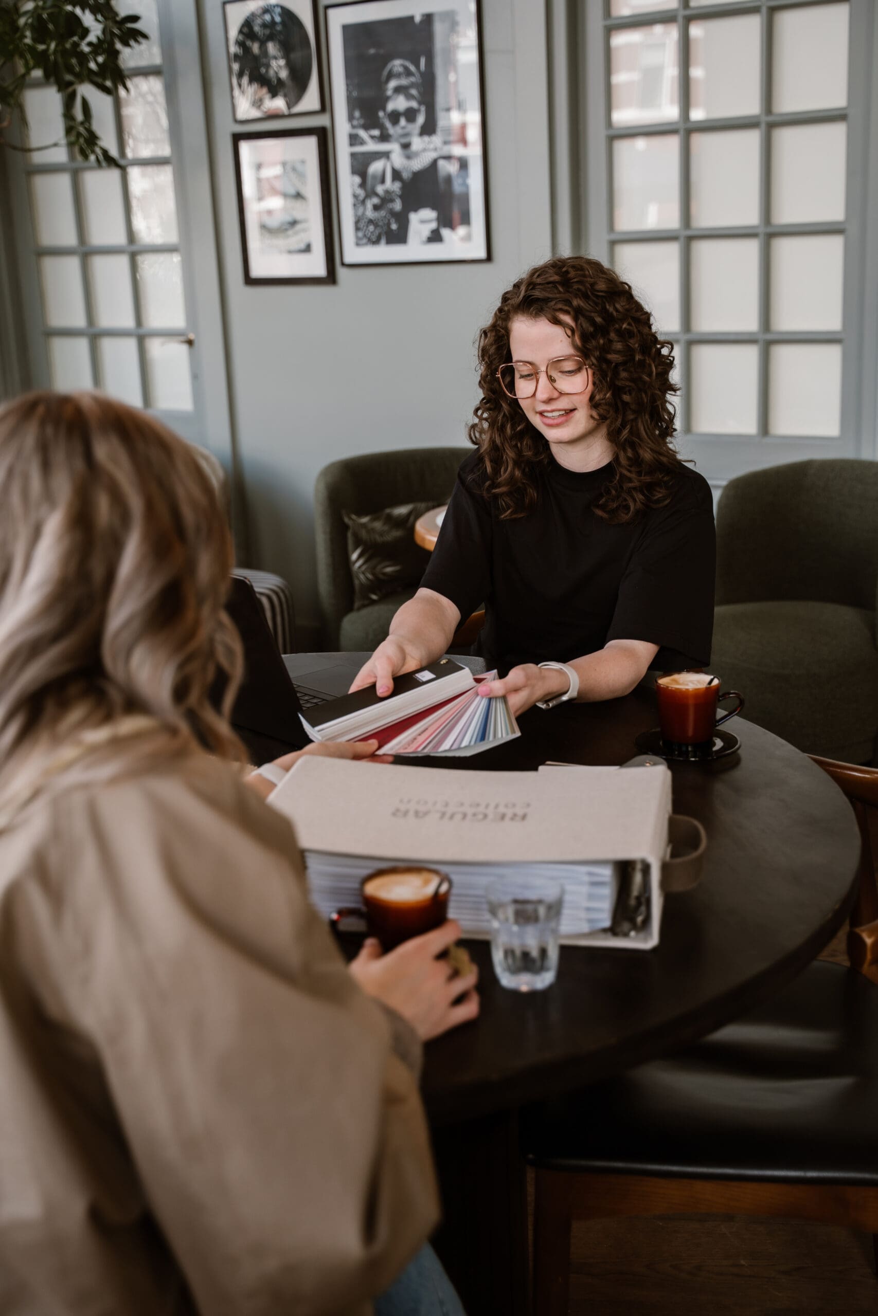 Interieurontwerper bespreekt kleurstalen met klant aan tafel tijdens een interieuradviesgesprek